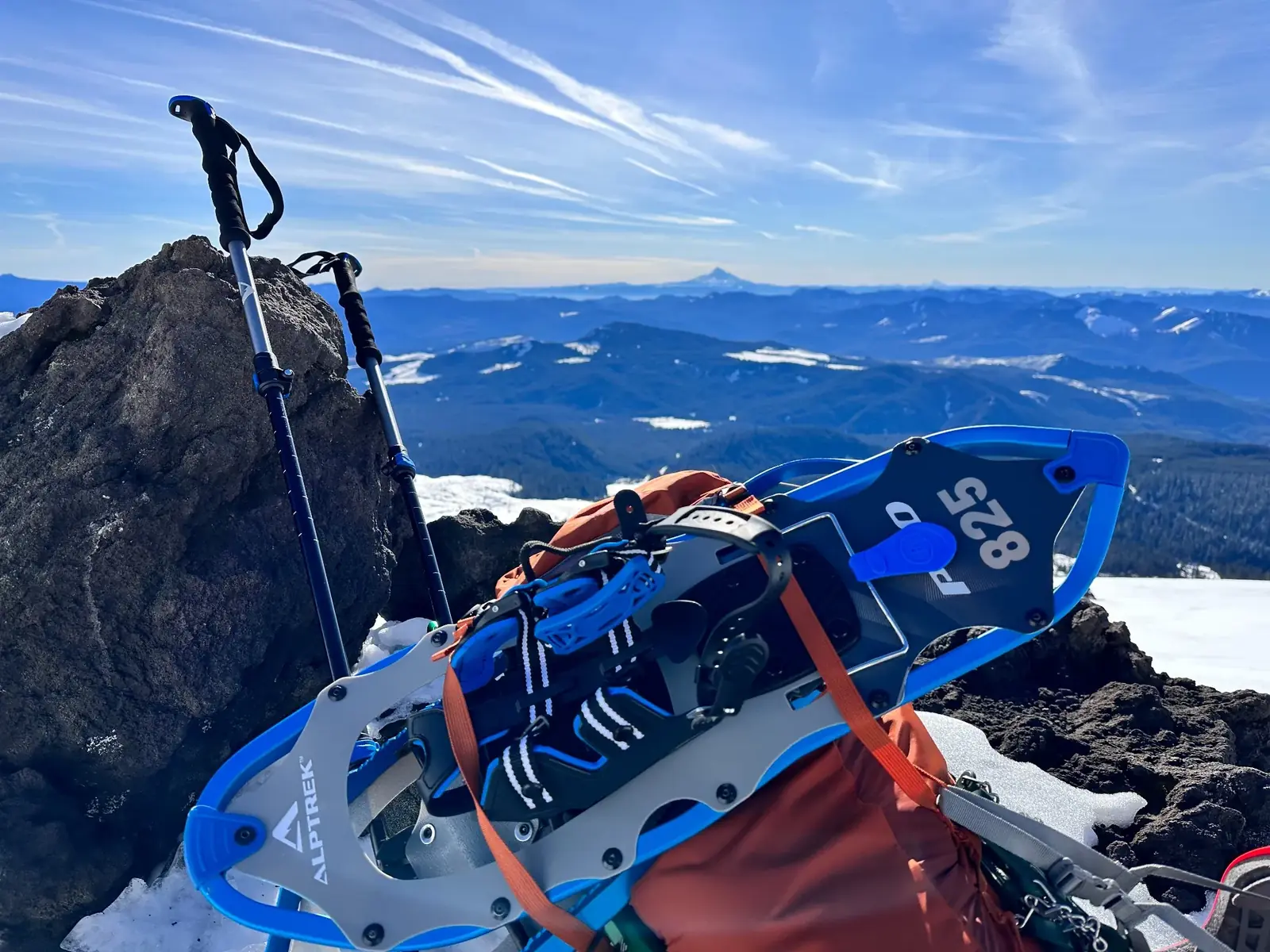 Snowshoes and trekking poles resting on volcanic rock above a mountain horizon