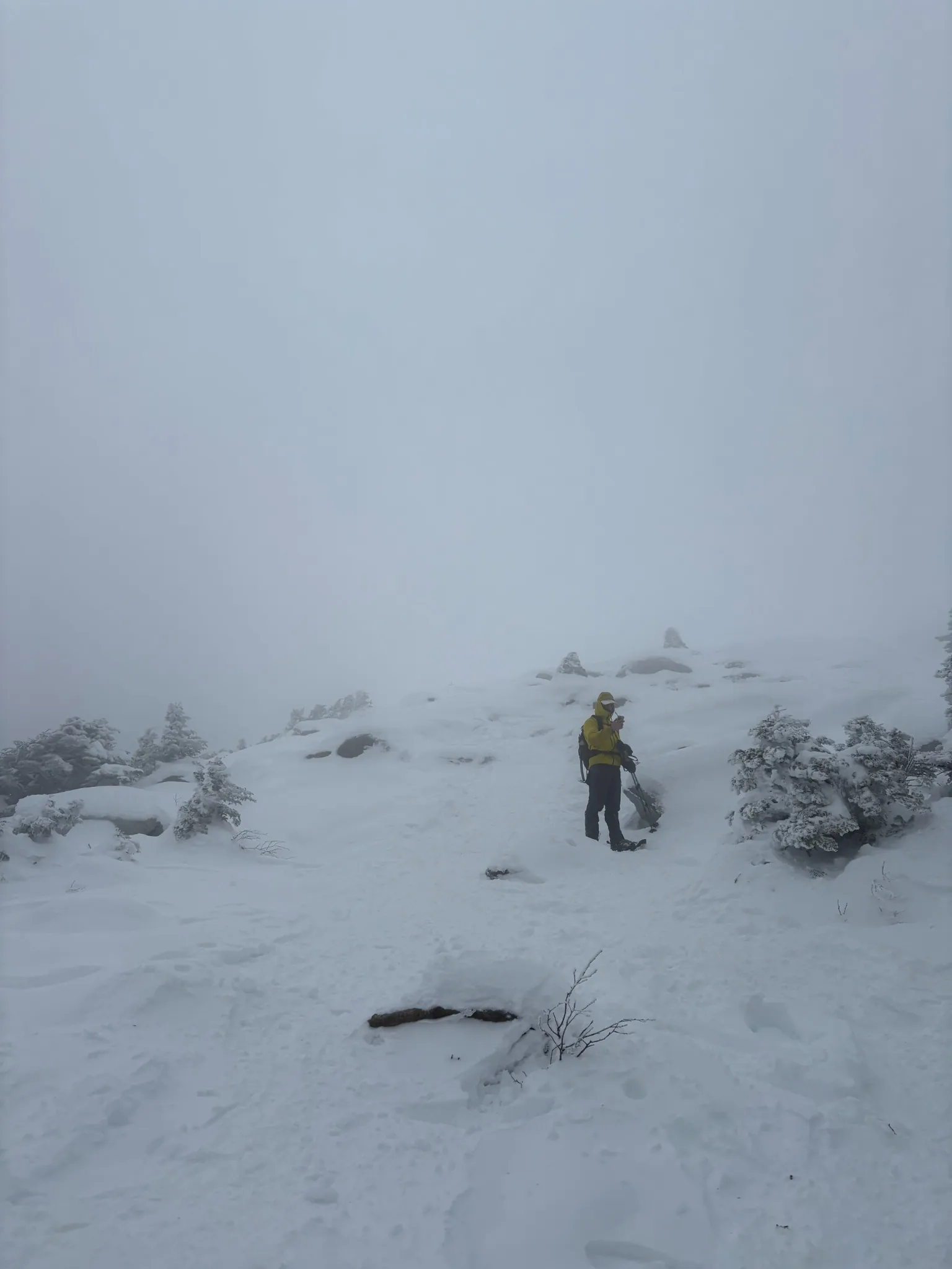 A climber standing in a whiteout on a snow-covered mountain