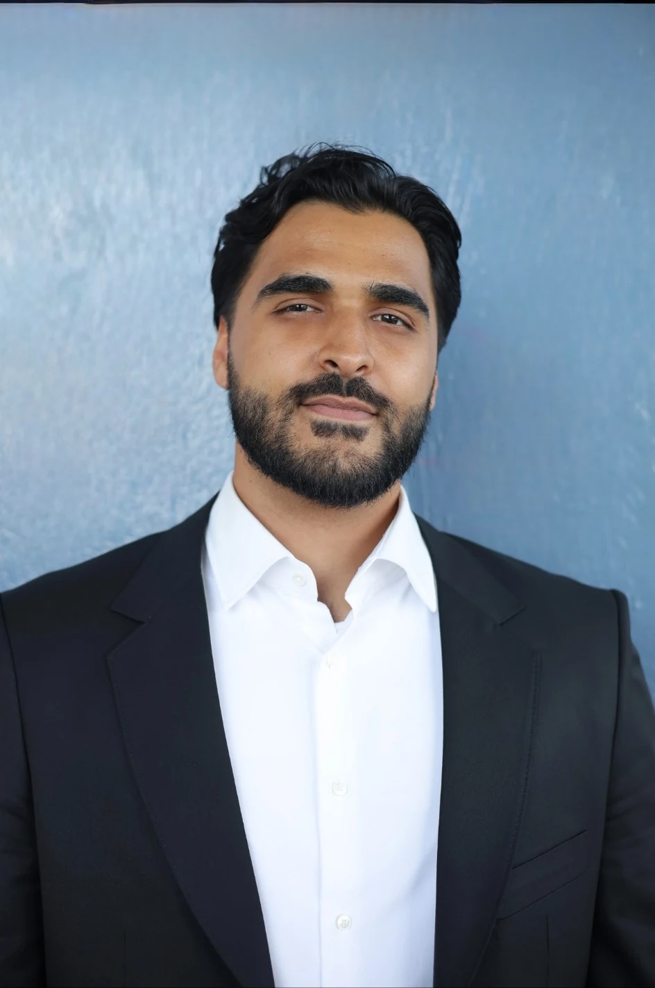 Professional portrait of Waleed Syed Faizi in a black suit and white shirt
