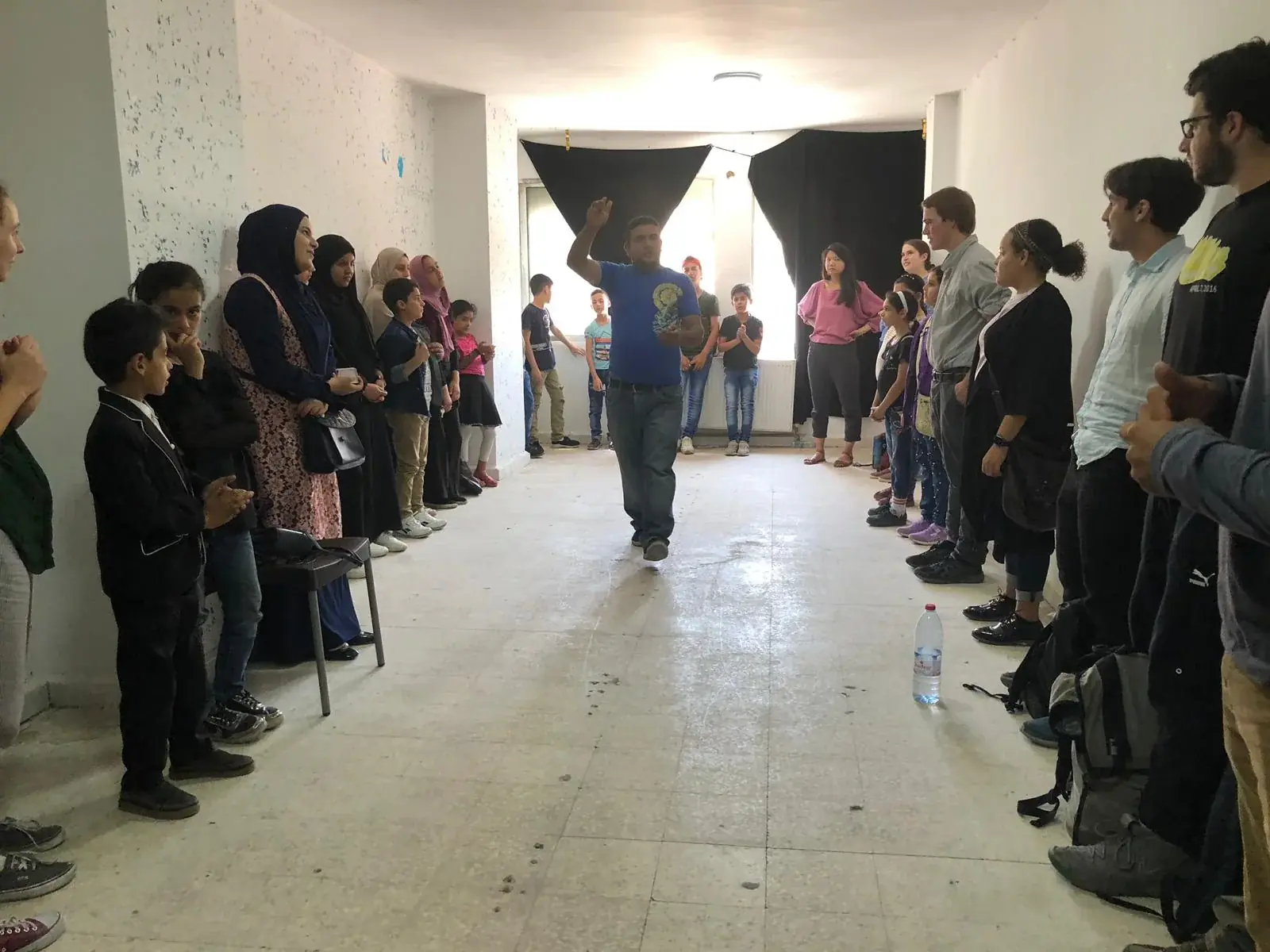 An instructor leading an English learning activity with children and volunteers in Jerash