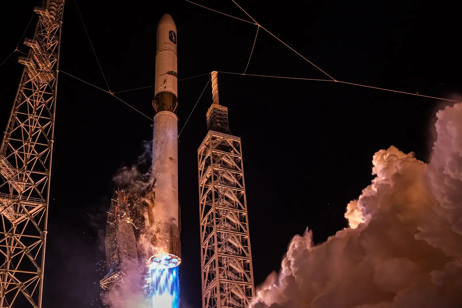 New Glenn rocket lifting from the launch pad at night amid bright exhaust and vapor